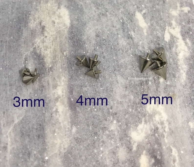 May include: Close-up of three sets of silver-colored cone-shaped studs with screw-on backs. The studs are labeled with sizes: 3mm, 4mm, and 5mm. The background is a light gray, textured surface.