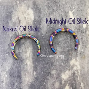 May include: Two rainbow-colored metal rings, one labeled "Naked Oil Slick" and the other "Midnight Oil Slick". The rings are made of stainless steel and have a iridescent finish.