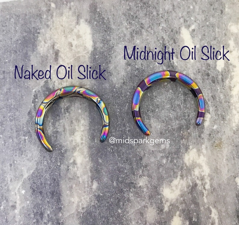 May include: Two rainbow-colored metal rings, one labeled "Naked Oil Slick" and the other "Midnight Oil Slick". The rings are made of stainless steel and have a iridescent finish.