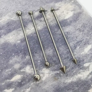 Puede incluir: Cuatro piercings de barra de acero quirúrgico con diferentes extremos. Dos tienen extremos de bola y dos tienen extremos puntiagudos.