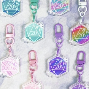 Könnte beinhalten: Acht Schlüsselanhänger aus Acryl mit einem D20-Würfel-Design in verschiedenen Farben, darunter Türkis, Rosa, Lila und Regenbogen, die jeweils die Zahl 20 anzeigen. Die Schlüsselanhänger haben Metallverschlüsse.