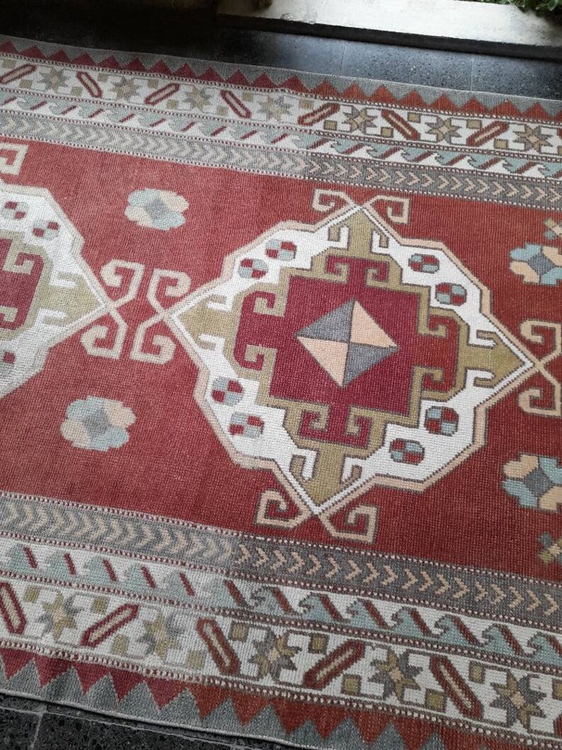 May include: A red, white, and blue patterned rug with a geometric design. The rug has a traditional Turkish kilim style.