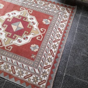 May include: A red, white, and blue patterned rug with a geometric design. The rug has a fringe border and is made of wool.