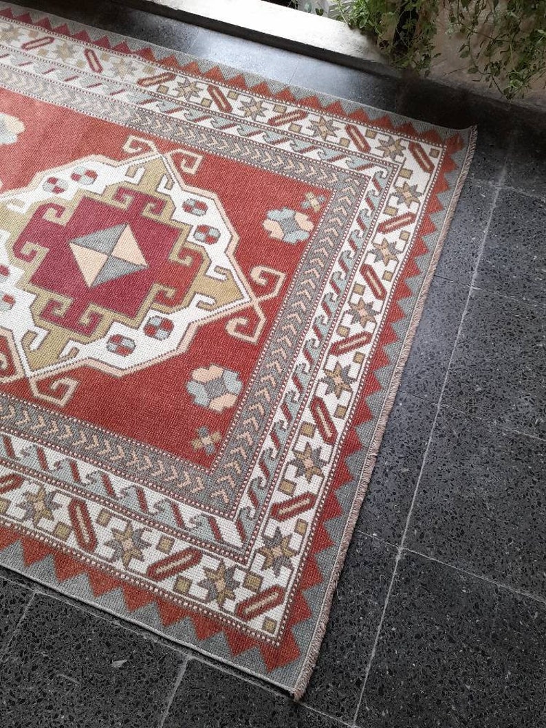 May include: A red, white, and blue patterned rug with a geometric design. The rug has a fringe border and is made of wool.