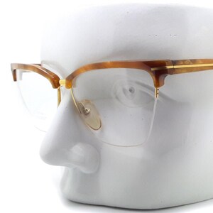 May include: Tortoiseshell eyeglasses with gold accents on a white mannequin head.