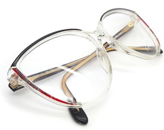 May include: Clear plastic eyeglasses with a black and red trim. The glasses have a cat-eye shape.