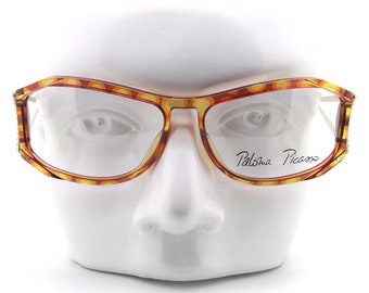May include: Tortoise shell eyeglasses with a clear lens and the signature "Paloma Picasso" printed on the right lens.