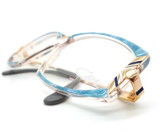 May include: Blue and gold patterned eyeglasses with a clear frame. The glasses have a gold accent on the side.