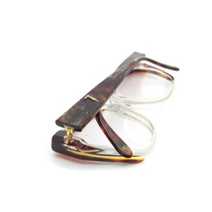 May include: A pair of tortoiseshell eyeglasses with clear lenses. The glasses have a gold hinge and a gold accent on the side.