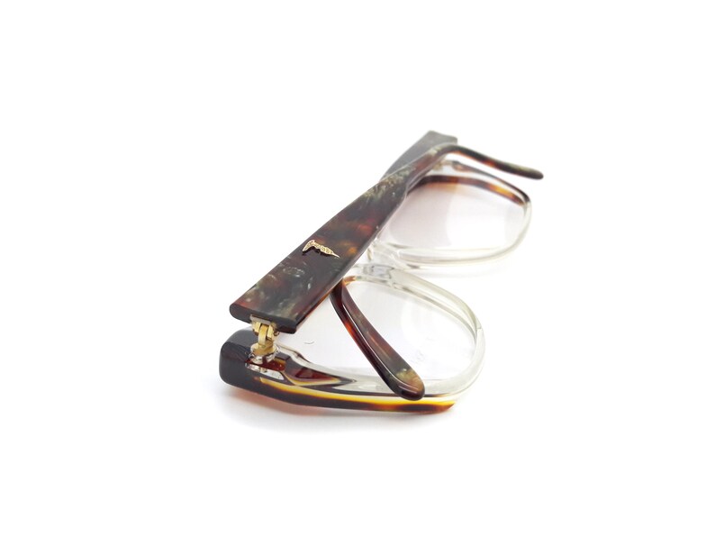 May include: A pair of tortoiseshell eyeglasses with clear lenses. The glasses have a gold hinge and a gold accent on the side.
