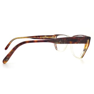 May include: Tortoise shell eyeglasses with a gold trim and clear lenses. The glasses have a cat-eye shape and are made of plastic.