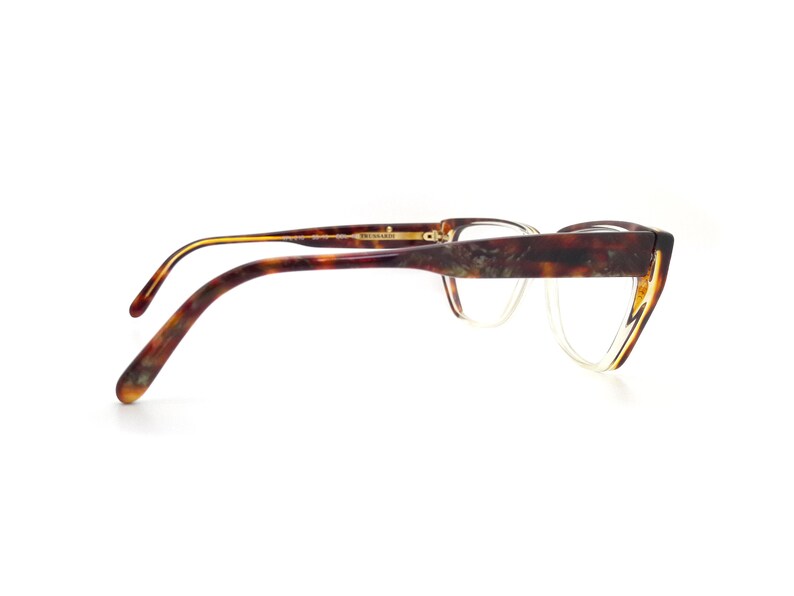 May include: Tortoise shell eyeglasses with a gold trim and clear lenses. The glasses have a cat-eye shape and are made of plastic.