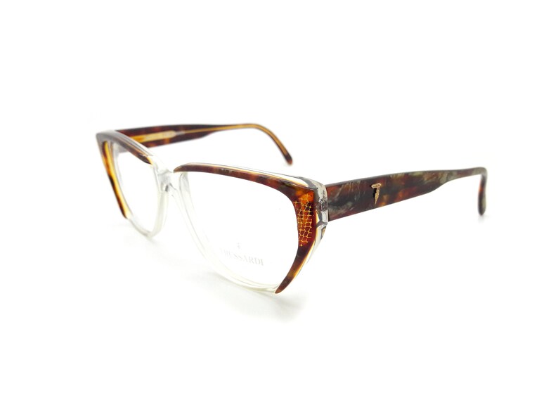 May include: Tortoise shell eyeglasses with clear lenses. The frames have a cat-eye shape and a gold T logo on the right temple.