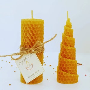 May include: Two handmade beeswax candles, one is a traditional honeycomb pillar candle and the other is a spiral honeycomb candle. The candles are labeled "Sunny Yellow" and "Handmade Candle".