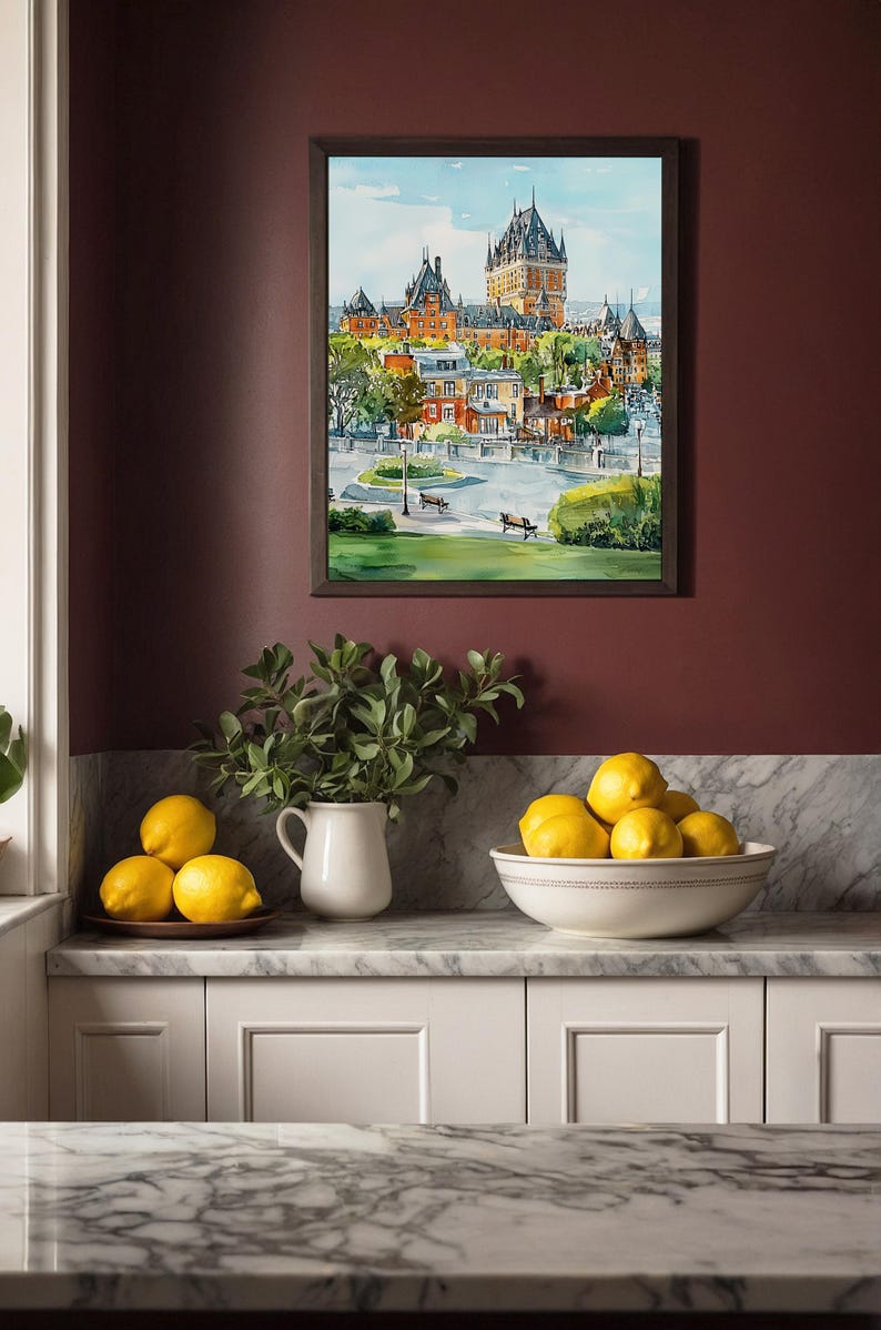 May include: A framed watercolor painting of a cityscape with a large castle-like building. The painting is displayed on a burgundy wall above a countertop with lemons in a bowl and on a plate, and a white pitcher with greenery.