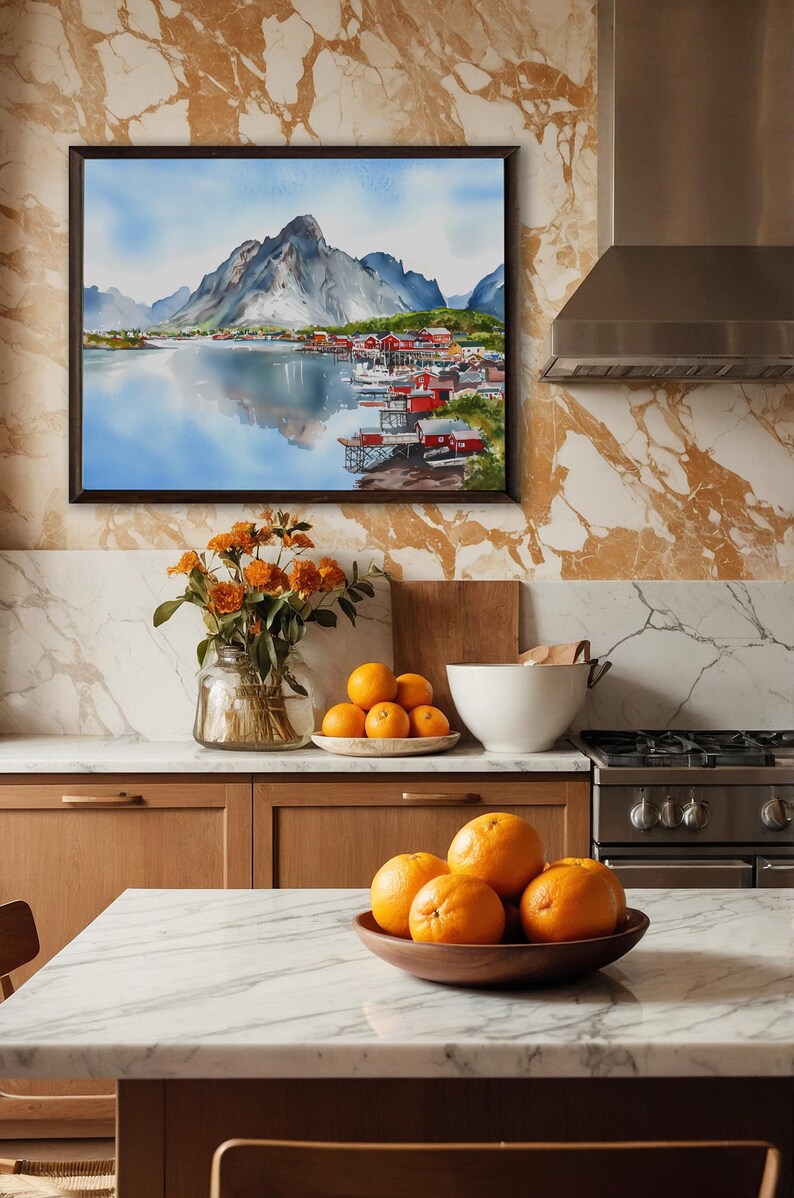 May include: A framed watercolor painting depicts a coastal village with red buildings nestled along a fjord, beneath a mountain range. The kitchen features a marble countertop, wooden cabinets, and a vase of orange flowers. Oranges are in a wooden bowl.