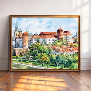 May include: Watercolor painting of a European cityscape in a gold frame. The artwork depicts buildings with red tile roofs, towers, and a green landscape under a blue sky. The painting is displayed on a wooden floor.
