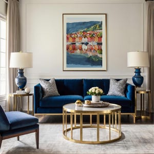 May include: A living room with a navy blue velvet sofa, two matching side tables with blue lamps, and a gold-framed coffee table. A framed watercolor painting of a colorful waterfront scene hangs above the sofa. Decorative pillows and a rug complete the space.