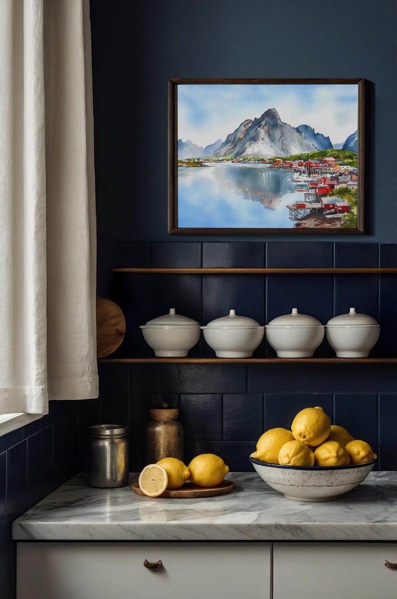 May include: A framed watercolor painting of a mountain landscape with a lake and village. Below, four white lidded bowls sit on a shelf. A bowl of lemons and a wooden plate with lemons are on a marble countertop.