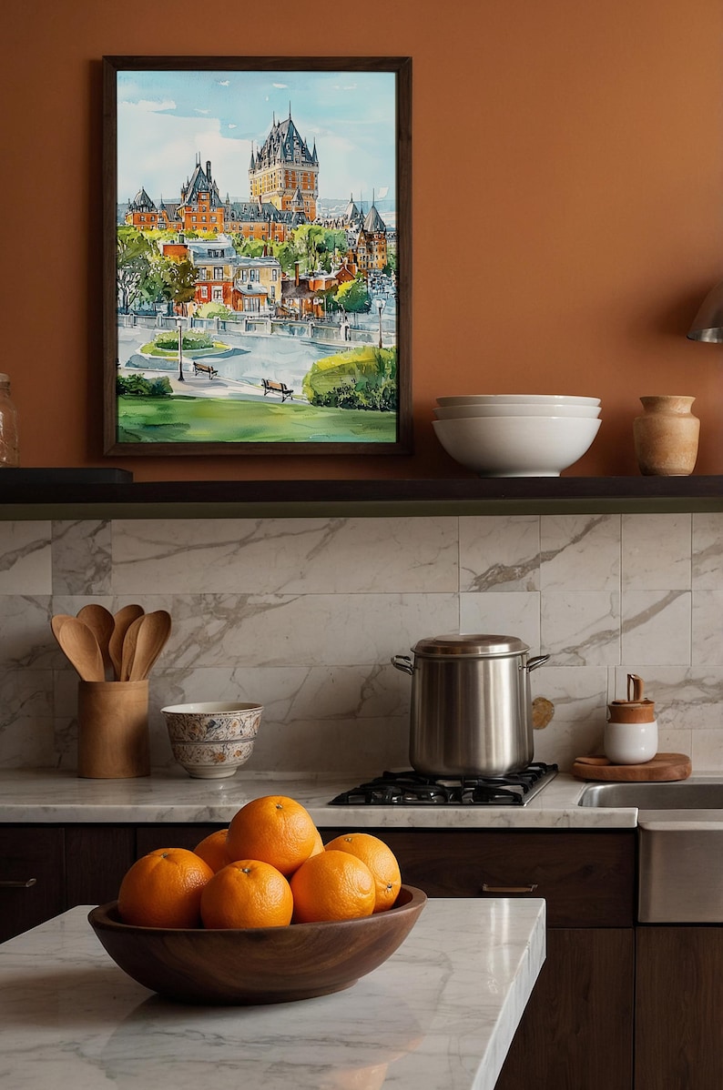 May include: A framed watercolor painting of a European city with a large castle. The painting is displayed above a kitchen shelf with white bowls and a ceramic jar. A wooden bowl of oranges sits on the counter.