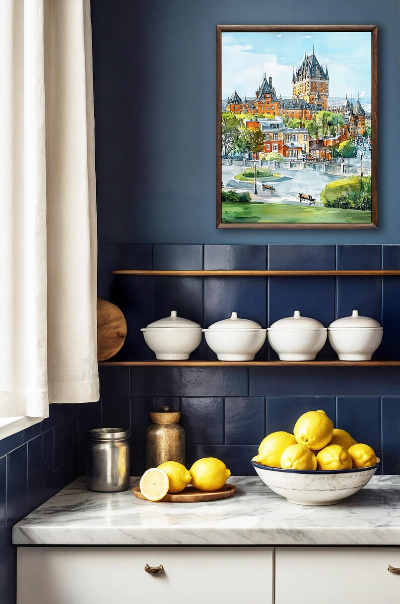 May include: A framed watercolor painting of a European cityscape hangs on a navy blue wall. Below, white ceramic bowls with lids sit on a wooden shelf. A bowl of lemons and a wooden cutting board are on the countertop.