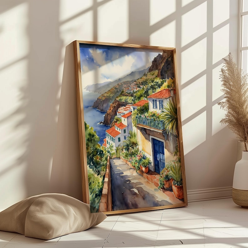 May include: Watercolor painting of a coastal town with colorful houses and a winding road leading down to the ocean. The painting features a blue door and lush greenery.