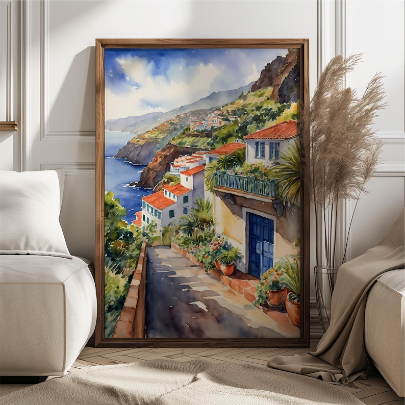 May include: Watercolor painting of a coastal village with white houses and red tile roofs. The houses are built on a hillside overlooking the ocean. The painting is framed in a wooden frame.