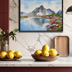 May include: A framed watercolor painting depicts a mountain landscape with a village by a lake. The painting is above a countertop with lemons in wooden bowls. A wooden tray and a vase with greenery are also on the counter.