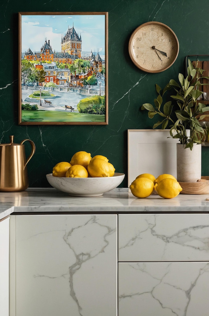 May include: A kitchen scene featuring a watercolor painting of a cityscape in a wooden frame, a gold pitcher, a white marble bowl filled with lemons, and a wooden clock. The background is a dark green marble wall.
