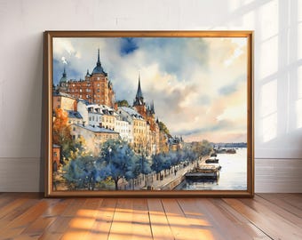 May include: A framed watercolor painting of a European cityscape. The artwork depicts buildings with spired roofs along a waterfront, with trees and boats. The color palette includes blues, oranges, and browns, with a golden frame.