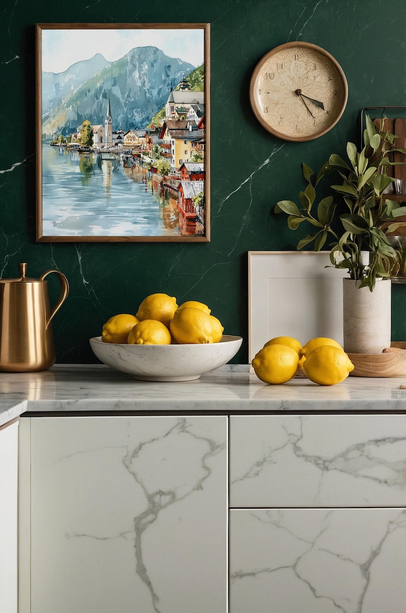 Peut inclure: Int&eacute;rieur de cuisine avec un tableau encadr&eacute; repr&eacute;sentant un paysage &agrave; l'aquarelle, une carafe dor&eacute;e et un bol de citrons. Une horloge ronde est accroch&eacute;e au mur en marbre vert fonc&eacute;. Le plan de travail est en marbre blanc.