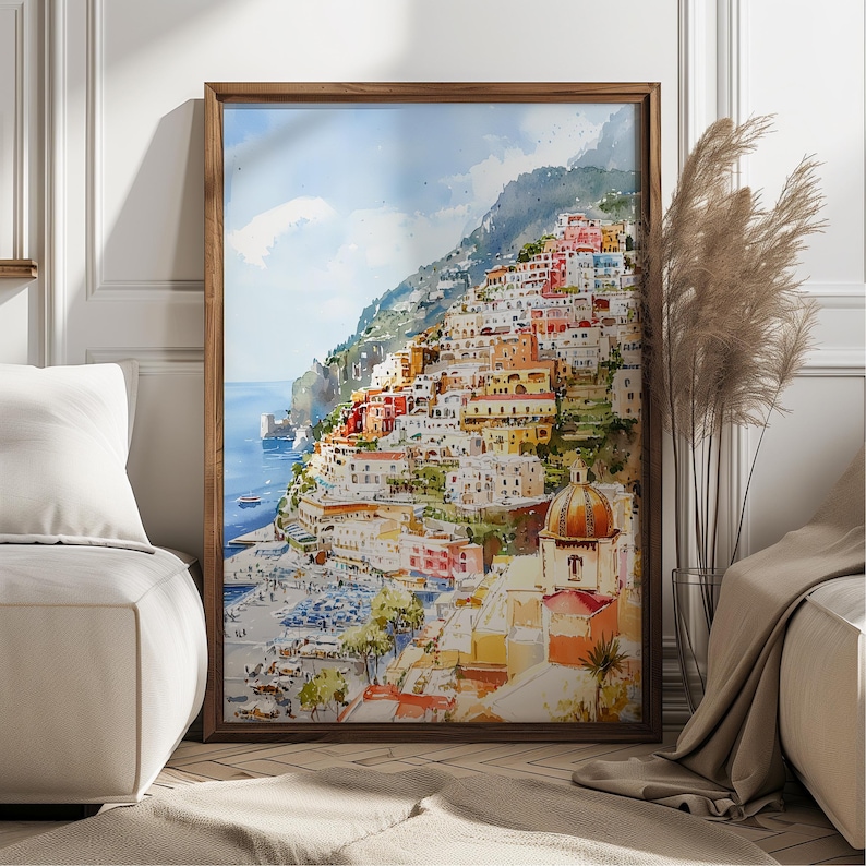May include: Watercolor painting of a coastal Italian town, featuring colorful buildings cascading down a hillside to the sea. The artwork is framed in a dark wood frame, with a blue sky and hints of boats in the water. The painting evokes a sense of travel and architecture.