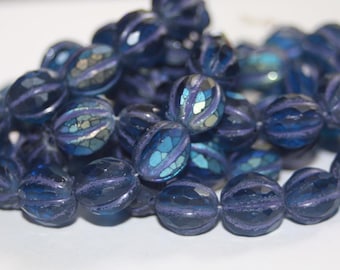 May include: A collection of dark blue, faceted beads with iridescent accents. Each bead has a unique pattern of color and texture, creating a shimmering effect. These beads are ideal for jewelry making.