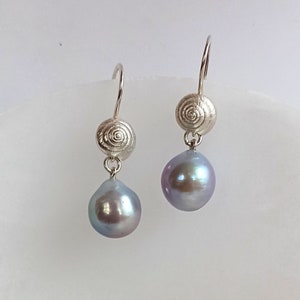 Puede incluir: Pendientes de plata con diseño de espiral y perlas grises iridiscentes en forma de lágrima. Los pendientes tienen cierre de gancho. Las joyas se muestran sobre un fondo blanco. Elegantes y adecuados para diversas ocasiones.