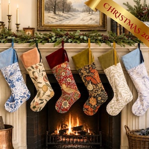 May include: Six decorative Christmas stockings hanging in a row, each featuring a unique floral or bird pattern with a solid velvet cuff. The stockings display various color palettes including blue, cream, red, and dark green, suspended by ribbons.
