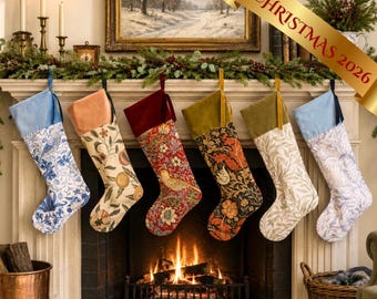 May include: Six decorative Christmas stockings hanging in a row, each featuring a unique floral or bird pattern with a solid velvet cuff. The stockings display various color palettes including blue, cream, red, and dark green, suspended by ribbons.