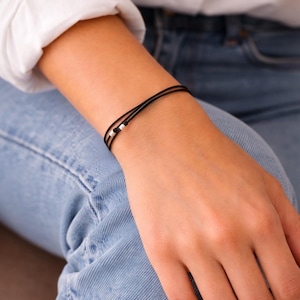 Bracciale con 3 cordini neri e 3 sottili perline tubolari in argento sterling. Gioiello originale, regolabile e realizzato a mano.
