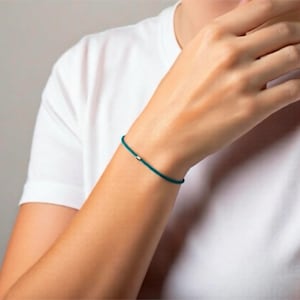 Armband mit einer kleinen Röhrchenperle, Sterlingsilber, türkisblaue Kordel. Verstellbar, dünn, dezentes Schmuckstück zum Kombinieren.