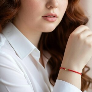 Braccialetto della Kabbalah con cordino rosso e 3 sottili perline tubolari in oro 14 carati. Un gioiello ideale come regalo per donne, uomini e bambini.