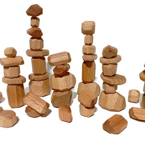 Peut inclure: Un ensemble de blocs d'empilage en bois en forme de formes géométriques irrégulières. Les blocs sont tous de couleur bois naturel et sont disposés en différentes piles et tas.