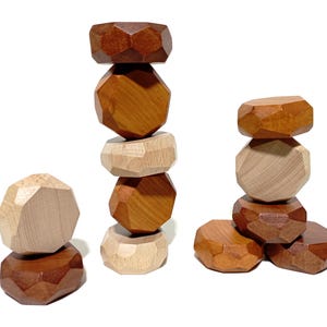 May include: A stack of wooden geometric blocks in brown and natural wood tones. The blocks are stacked in a tower with a few blocks on the bottom forming a base.