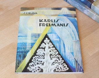 May include: A book cover with a blue, yellow, and white abstract design. The title "KARLIS FREIMANIS" is printed in black letters. The author's name "J. CIELAVA" is printed in the top left corner.