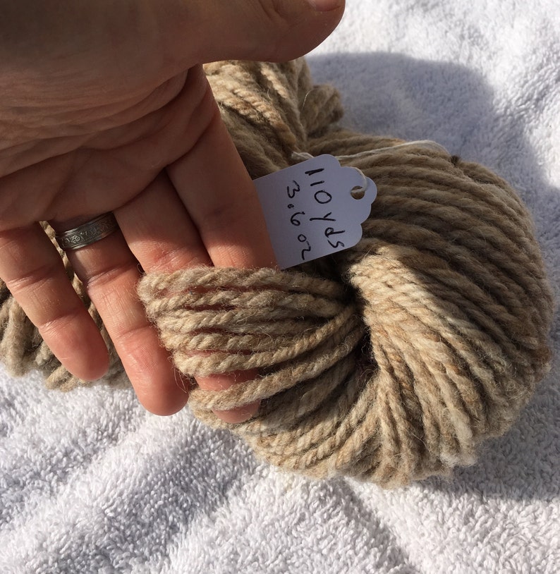 May include: A skein of beige yarn with brown highlights. The yarn is labeled "110 yds 3.16 oz".