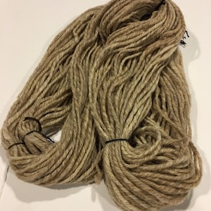 May include: A skein of beige yarn with a subtle brown and white variegation. The yarn is made of natural fibers and is perfect for knitting or crocheting.