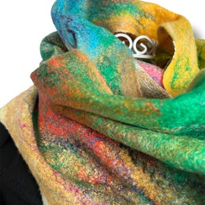 Puede incluir: Bufanda multicolor afieltrada a mano, con una mezcla de tonos vibrantes como azul, verde, amarillo y rojo. La bufanda tiene una apariencia texturizada y está drapeada, mostrando su intrincado diseño y artesanía. Una pieza de arte portátil.