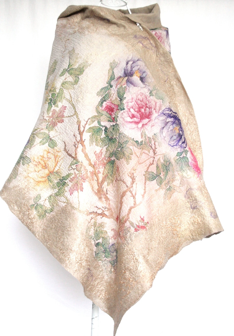 K&ouml;nnte beinhalten: Beiger Schal mit floralem Design mit rosa, lila und gelben Blumen. Der Schal hat eine strukturierte Oberfl&auml;che und einen dekorativen Rand. Die Blumen sind vor einem hellen Hintergrund mit einem Baumzweigmuster angeordnet.