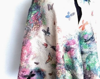 Könnte beinhalten: Ein weißer Wollschal mit einem farbenfrohen abstrakten Design und Schmetterlingsmustern. Der Schal ist über eine Schaufensterpuppe gelegt.