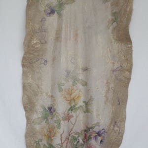 K&ouml;nnte beinhalten: Ein langes, rechteckiges Textil mit floralem Design. Der Stoff hat einen cremefarbenen Hintergrund mit rosa, lila und gelben Blumen und gr&uuml;nen Bl&auml;ttern. Die R&auml;nder sind mit einem goldenen Rand versehen.