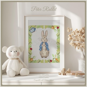 May include: Cross stitch pattern of Peter Rabbit in a blue jacket, standing in a green garden with a butterfly. The pattern is labeled "PDF Pattern" and "Compatible with Pattern Keeper".