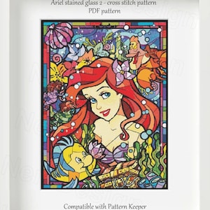 May include: Cross stitch pattern of Ariel from The Little Mermaid in a stained glass style. The pattern features Ariel with her red hair, a purple seashell bra, and a green tail. She is surrounded by sea creatures, including Flounder and Sebastian. The pattern is compatible with Pattern Keeper.